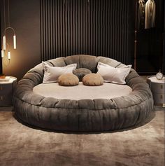 a large round bed with pillows on top of it in the middle of a room