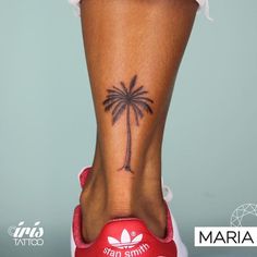 a woman's foot with a small palm tree tattoo on her left side ankle