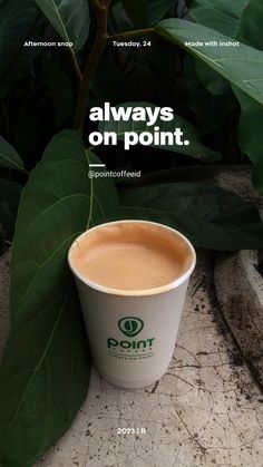 a cup of coffee sitting on top of a table next to some green leafy plants