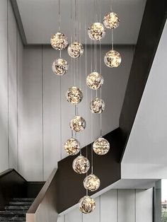 a modern chandelier hanging from the ceiling in a room with white walls and stairs