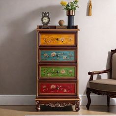 a colorful dresser with flowers on it next to a chair