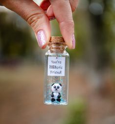 a person holding a tiny bottle with a panda in it