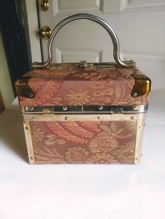 "VINTAGE DELILL Box Purse// 1950/60's Glamour Girl Train Case// Retro  Handbag Made in Italy// Mid Century Makeup Case.  This purse features a Brocade Gold and Brown finish, the lining is a beautiful shiny Gold.  DELILL, is the name that is synonymous with beauty and glamour.  This purse has stood the test of time, the lining and body, and hardware are in good vintage condition.  DIMENSIONS:  Width - 8\" X  Height - 6.5'' X  Depth - 5.5\" Our vintage finds, are all pre-owned and pre-used. Please expect your item to show signs of both, we inspect our items, and endeavor to give you the most accurate description possible. If you need more photos or information, please feel free to talk with us. Our FAQ's information is part of the listing description. THANK YOU!" Vintage Double Handle Box Bag For Travel, 1950s Purses Vintage Handbags, 1960s Handbags, 1960s Purse, Vintage Makeup Train Case, Girl Train, Retro Handbags, Makeup Train Case, Train Case