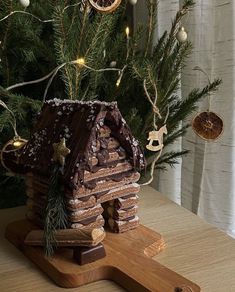 a gingerbread house on a cutting board under a christmas tree