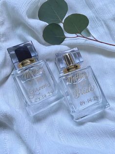 two perfume bottles sitting on top of a white sheet