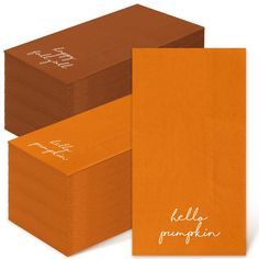 three orange napkins with the words hello pumpkin printed on them, and one folded in brown paper