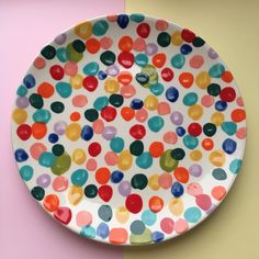 a colorful polka dot plate on a pink and yellow wall next to a white background