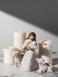 a small figurine holding a baby jesus next to some candles on a table