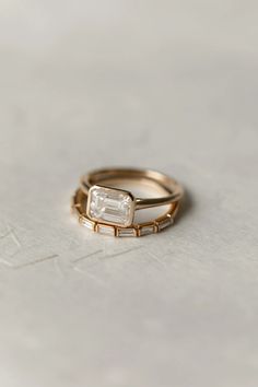 two gold rings with an emerald stone on the top and one diamond in the middle