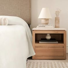 a bedroom with a bed, nightstand and lamp on top of the night stand in front of the bed