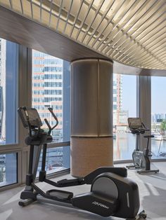 an exercise room with treadmills and machines in front of large windows overlooking the water