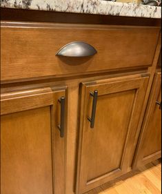 a kitchen with wooden cabinets and granite counter tops in the center, along with a stainless steel door handle