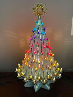 a colorful christmas tree made out of plastic beads and other decorations on a table top