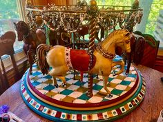 a carousel with two horses on it in the middle of a room next to a window