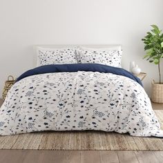 a bed with blue and white comforters in a room next to a potted plant