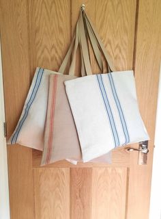 three folded towels hanging from a door handle on a wooden door with a white and blue striped bag next to it