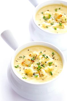 two white bowls filled with soup on top of a table