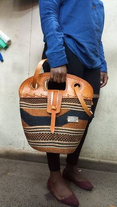 "Brown and black sisal tote bag with leather flap DIMENSIONS Bottom width: 10\" Top width: 14\" Depth: 10\" Straps: 15\" SHIPPING All orders ship via DHL Express (3-5) days delivery time." Brown Bucket Shoulder Bag With Handles, Top Handle Natural Bucket Bag For Market, Natural Top Handle Bucket Bag For Market, Eco-friendly Shoulder Bag With Detachable Handle, Eco-friendly Shoulder Bag With Detachable Handle For Everyday, Daily Use Bucket Satchel With Top Carry Handle, Handheld Eco-friendly Shoulder Bag With Detachable Handle, Handwoven Leather Bucket Bag For Daily Use, Handwoven Leather Hobo Bag