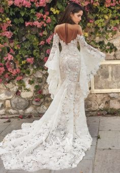 the back of a woman's wedding dress with long sleeves and flowers on it