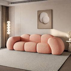 a pink couch sitting on top of a rug in a living room next to a window