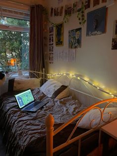 a laptop computer sitting on top of a bed in a room with pictures hanging on the wall