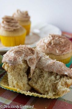 two cupcakes with frosting and cinnamon sprinkles sitting on a table