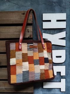 This vintage crochet shoulder bag is hand crocheted with a patchwork design in cotton yarn. It comes in a brown tone with a variety of color shades, including beige, orange, yellow, grey, and cream. The pattern is composed of small individual squares and rectangles. Each is crocheted in a different color, creating a vibrant effect. The crochet bag features dark brown genuine leather straps. It has a cotton lining interior with side pockets and a secure zip closure. The edges of this handmade tot Brown Rectangular Patchwork Shoulder Bag, Brown Patchwork Rectangular Bag, Brown Rectangular Patchwork Bag, Rectangular Brown Patchwork Bag, Everyday Brown Patchwork Shoulder Bag, Brown Crochet Tote Bag With Granny Square, Brown Hand-knitted Crochet Tote Bag, Brown Hand-knitted Rectangular Bag, Brown Granny Square Crochet Tote Bag