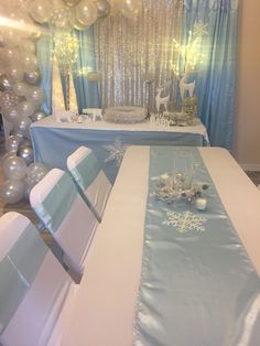 a table set up for a baby's first birthday party with balloons and snowflakes