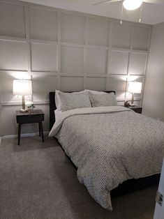 a bedroom with a bed, nightstands and two lamps on either side of the bed