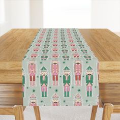 a table with a green and pink christmas pattern on it, along with two wooden chairs