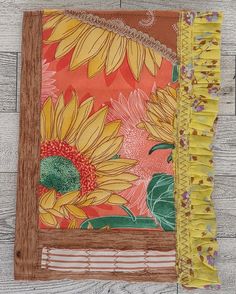 an orange and yellow quilt with sunflowers on the front, sitting on a wooden floor