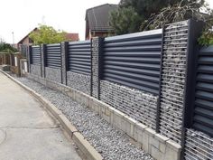 a long black fence is next to a graveled area with rocks on the side