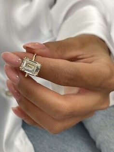 a woman's hand holding a ring with a diamond in the middle and a baguette on it