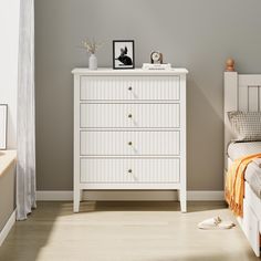 a white dresser sitting next to a bed in a bedroom