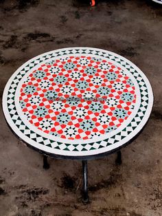 a table that is sitting on the ground with an orange and black design on it