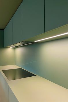 an empty kitchen with white counter tops and blue cabinets in the back drop off area