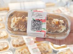 a person holding up a plastic container with some food in it and a qr code on the label