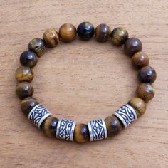 Designed for men by Balinese artisan Asmara Putra this stretch bracelet circles the wrist with beads of natural tiger's eye. At the front of the bracelet the tiger's eye alternates with four sterling silver beads that feature intricate patterns.