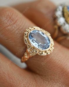 a woman's hand with two rings on it and an oval blue stone in the middle