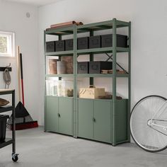 a bike is parked next to a green bookcase in a room with white walls