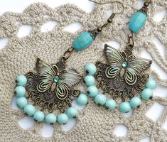 "Flirty chandelier earrings featuring filigree butterfly accents on embossed antiqued pendants that swing over dangling pale turquoise blue glass beads! Each of the butterflies are accented with painted touches of sea foam green & turquoise and little Swarovski crystal rhinestones sparkle in their centers! Each unique pendant dangles from genuine magnesite beads, too, which are thought to aid in meditation and creativity! Just dangle this unique pair from your ears to add fun, Boho style to Bohemian Butterfly Charm Jewelry For Jewelry Making, Bohemian Jewelry With Butterfly Charm For Jewelry Making, Bohemian Butterfly Jewelry, Bohemian Dangle Jewelry With Butterfly Charm, Bohemian Jewelry With Butterfly Charm Dangle, Bohemian Butterfly Nickel-free Jewelry, Bohemian Butterfly Jewelry With Pierced Design, Light Blue Bohemian Dangle Jewelry, Nickel-free Light Blue Bohemian Jewelry