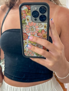 a woman holding up her phone case with flowers on it