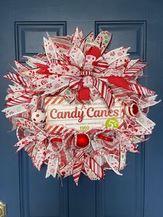 a candy cane christmas wreath hanging on a blue door with candy canes written on it