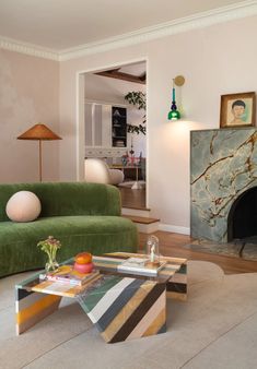 a living room filled with furniture and a fire place next to a green couch on top of a hard wood floor