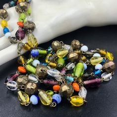 "This is one of my favorite types of necklaces to find. It's a LONG flapper style - over the head with no fastener/clasp - necklace made from SMALL wired art glass beads. The multi-colored beads are lovely with some being more \"solid\" in terms of color and others being more \"clear\" or \"transparent.\" The different shaped beads are wired together. There are 12 orb shaped brass beads evenly interspersed among the glass beads. I think the necklace is most likely a 1970s reproduction rather than a true 1920s/1930s flapper era necklace. For this reason, I was hesitant to date it but know it to be vintage by Etsy's standards. The beads could be Czech glass or even made in Japan. The necklace can be worn long or doubled. It has a HANG length of 29 inches. The width of the necklace varies wit Vintage Czech Glass Beaded Necklace, Faceted Round Beads Necklace For Jewelry Making, Vintage Glass Beaded Necklaces With Oval Beads, Vintage Adjustable Beaded Necklace With Polished Beads, Adjustable Vintage Beads For Jewelry Making, Vintage Adjustable Faceted Beads, Vintage Beads For Jewelry Making, Vintage Faceted Beaded Necklace, Vintage Large Beads For Jewelry Making