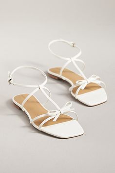 The Reformation Maya Bow Sandals feature a square toe, ankle strap, and delicate bow at the toe for a sweet springtime sandal. | Maya Bow Sandals by Reformation in White, Women's, Size: 6.5, Leather/Rubber at Anthropologie Feminine Low Heel Sandals With Bow, Chic Low Heel T-strap Sandals For Spring, Chic Flat Heel T-strap Sandals For Spring, Summer Bow Sandals With Square Toe, Spring Ankle Strap Sandals With Bow Straps, Spring Lace-up Sandals With Low Heel And Heel Strap, Square Toe Bow Sandals For Summer, Party Sandals With Bow And Square Toe, White T-strap Sandals For Spring Party