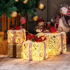 two teddy bears sitting on presents under a christmas tree with lights and decorations around them