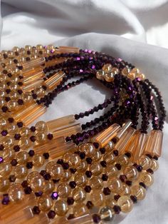 Why You'll Love It: Striking Design: The rich purple crystal glass beads paired with the warm golden sandy brown accents create a luxurious and timeless aesthetic. Premium Quality: Crafted with high-quality glass beads, ensuring durability and lasting brilliance. Comfortable Fit: The elastic design offers a comfortable and flexible fit for all-day wear. Versatile Style: Perfect for everyday wear, special occasions, or as a thoughtful gift. Cultural Significance: Purple: In Ivorian culture, purpl Brown Gold Beads Jewelry For Party, Brown Glass Beads For Jewelry Making, Brown Faceted Beads Jewelry For Party, Elegant Brown Beaded Necklace For Party, Brown Beaded Necklaces With Round Beads For Party, Gold Crystal Beaded Necklaces With Gemstone Beads, Gold Crystal Necklaces With Faceted Beads For Party, Elegant Brown Beaded Necklace With Gemstone Beads, Elegant Amber Crystal Necklaces With Polished Beads