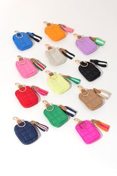 small purses are lined up together on a white surface and one has a keychain in the middle