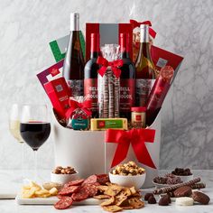 the wine and snacks gift basket is filled with red wine, cheeses, crackers, and nuts